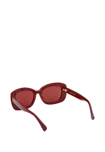 Gafas de sol de plástico rojo con diseño de ojos de gato, lentes tintados en rojo oscuro y detalles sutiles de metal dorado en las patillas. Acabado liso y textura brillante.