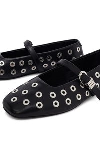 Ballerine in pelle nera con punta quadrata, occhielli decorativi in argento e una tracolla regolabile con una fibbia rettangolare in argento.