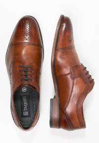 Chaussures habillées en cuir marron avec des détails perforés, un design classique à lacets, une texture lisse et un talon bas empilé.