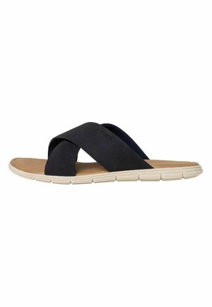 Sandales glissantes bleu marine foncé avec des brides entrecroisées, en matériau doux semblable à du daim, et une semelle coussinée beige clair avec des rainures horizontales.