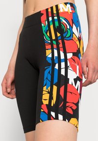 Svarta tightsshorts med ett färgglatt blommönster på ena sidan, prydda med tre svarta vertikala ränder. Tillverkade i stretchigt material.