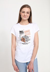 Biała bawełniana koszulka z krótkim rękawem, z blokowym wzorem graficznym oraz napisem "BUDUJ, TWÓRZ, ZWIEDZAJ" w pomarańczowym i czarnym kolorze.