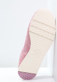 Rosa sneaker med texturerad överdel, gummisula och hexagonmönster. Har vit mellansula och logotyp på undersidan.