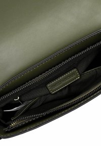 Intérieur d'un sac en faux cuir vert avec doublure en tissu noir, fermeture à glissière et une étiquette affichant "EMILY & NOAH".