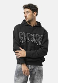 Schwarzes Kapuzenshirt mit großem, weißem Grafiktext "CIPOBAXX" auf der Brust. Verfügt über eine Kängurutasche und eine vordere Kapuze, aus einem strukturierten Stoff gefertigt.