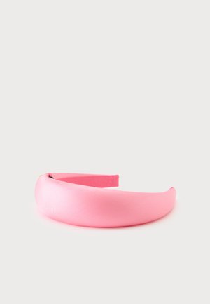 Bandeau large en tissu rose rembourré avec une texture lisse sur fond blanc.