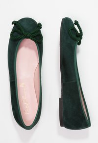 Ballerine in suede verde con punta rotonda, fiocco decorativo in corda verde e soletta rosa chiaro. Suola piatta con minimal tread.