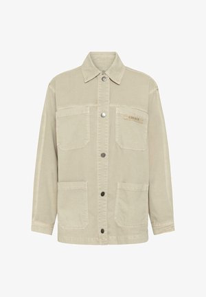 Bézs gombos dzseki négy foltzsebbel, hosszú ujjakkal és gallérral; kis "LIBERTE" címke a jobb felső zsebben.