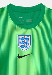 Zeleni Nike Dri-FIT dres z navpičnimi črtami, črnim logotipom in vezenim grbom Anglije s tremi levi in rdečimi cvetlicami.