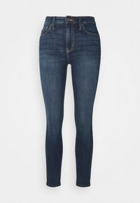 Tajta jeans i mörkblå denim. Högmidjad design med fem fickor, subtila sömnadsdetaljer och en slät yta.