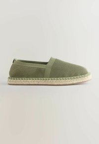 Espadrille en filet vert olive à enfiler avec semelle en jute tressé et languette de tirage sur fond clair uni.