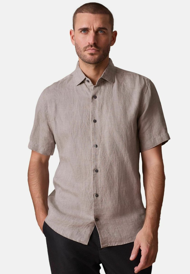 Leinenhemd mit kurzen Ärmeln in hellem Beige mit strukturierter Oberfläche, versehen mit durchgehendem Knopfverschluss und kleinen dunklen Knöpfen.