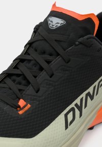 Μαύρο αθλητικό παπούτσι με υφή από ύφασμα, πορτοκαλί λεπτομέρειες και διακριτό λογότυπο. Διαθέτει μαξιλαρωτή σόλα και παραδοσιακό σύστημα δέσιμου.