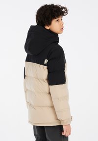 Giubbotto imbottito in beige e nero, dotato di cappuccio, texture trapuntata, polsini elasticizzati e dettagli con logo sulla parte superiore sinistra.