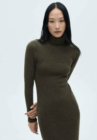 Robe ajustée vert olive avec un col montant imitation et des manches longues, fabriquée dans un tissu tricoté texturé, présentant une silhouette lisse.