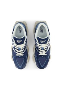 Pair of navy blue and white New Balance 9060 sneakers with beige chunky soles, white laces, and mesh and suede upper material, top view.