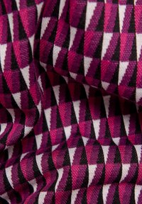 Textil mit geometrischem Muster in Nuancen von Pink, Lila, Schwarz und Weiß, das eine strukturierte, gewebte Optik und einen sanften Fall aufweist.