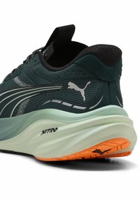 Ciemnoniebieskie buty biegowe z lekką siateczkową cholewką, kontrastującą miętową podeszwą środkową i pomarańczową gumową podeszwą. Zawierają logo Puma po boku.