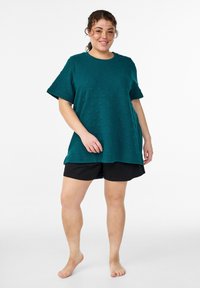 Tyrkysový top s krátkými rukávy a texturovaným vzorem, doplněný černými šortkami. Top má kulatý výstřih a volný střih, vhodný pro běžné nošení.