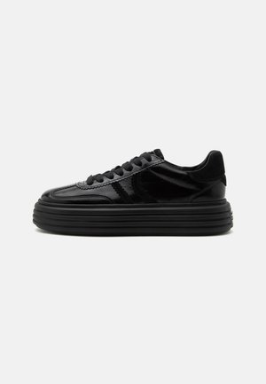 Czarny błyszczący sneaker na platformie z grubą, żebrowaną podeszwą, sznurowany z przodu, z widocznymi przeszyciami z boku.