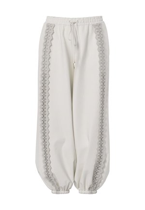 Pantalon blanc coupe ample avec poignets et taille élastiques, présentant une bordure en dentelle verticale le long des deux jambes et un cordon à l'avant.