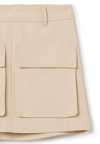 Beige denimrok met een aansluitende taille, twee grote voorzakken en een rechte vorm. Soepele textuur en nette, eenvoudige stiksels.