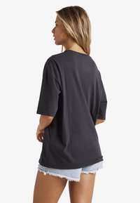 Sort oversized t-shirt lavet af bomuld med korte ærmer, rund halsudskæring og en afslappet pasform, parret med denimshorts.
