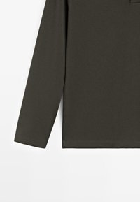 Bluzka z długim rękawem w ciemnooliwkowej bawełnie, z zaokrąglonym dekoltem i dyskretnym przeszyciem wzdłuż krawędzi oraz mankietów.