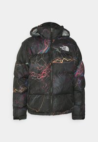 Svart puffjacka med flerfärgade abstrakta linjemönster, frontdragkedja, huva och vit The North Face-logotyp på bröstet.