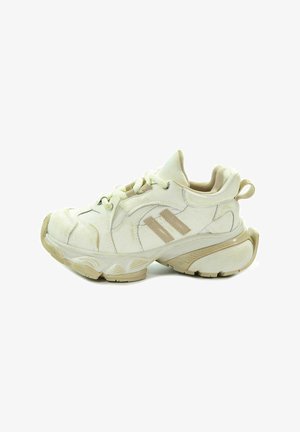 Białe sportowe buty z beżowymi akcentami, teksturowana cholewka, okrągły nosek, wyściełany kołnierz i gruba gumowa podeszwa z wyraźnym wzorem bieżnika.