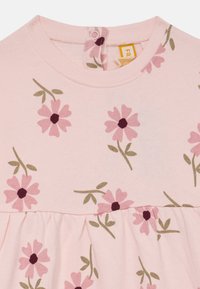 Robe en coton rose avec un col rond et une fermeture à boutons dans le dos. Le tissu est orné de fleurs roses et de feuilles vertes.