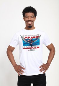 Camiseta de algodón blanca con un diseño gráfico de Capitán América con alas, fondo azul y texto rojo, estilo ajustado y mangas cortas.