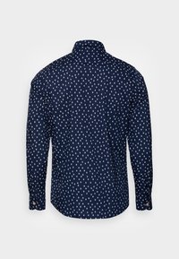 Camisa de botones navy con un patrón de diamantes y cuadrados blancos. Mangas largas, cuello y dobladillo redondeado. Presenta puños abotonados con acentos de color.