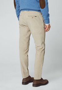 Beiga manchesterbyxor med rak passform, med bakfickor och subtil textur, i kombination med bruna läderstövlar.