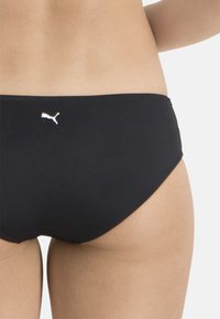 Schwarzer Bikini-Unterteil aus glattem, dehnbarem Material. Verfügt über ein kleines weißes Puma-Logo und ein mittelhohes Design mit klaren Linien.