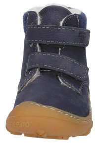 Marineblaue Leder-Stiefelette mit zwei Klettverschlüssen, weißem Futter aus Kunstpelz und einer sandfarbenen Gummisohle. Genähte Akzente entlang der Nähte.