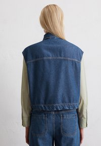Denim vest met een kraag, mouwloos ontwerp en een iets oversized pasvorm. Voorzien van versterkte stiksels en een klassieke blauwe kleur.