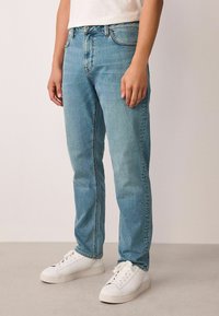 Lyseblå denimjeans med lige ben, der har et klassisk design med fem lommer, falmet tekstur og en subtil kontrastsyningsdetalje.