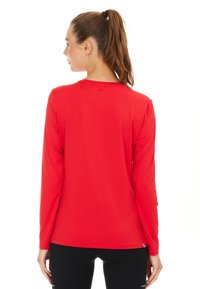 Rotes langärmeliges Sportshirt aus glattem, dehnbarem Stoff. Mit Rundhalsausschnitt und einer körpernahen Passform, die bis zur Taille reicht.