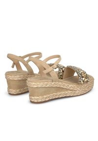 Sandalias de cuña beige con suelas de yute trenzado, tiras cruzadas y adornos con acentos en cristal y dorado. Textura suave de ante.