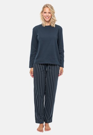 Marinblå bomullströja med långa ärmar i kombination med marinblå och vita randiga pyjamasbyxor; avslappnad passform och mjukt material. Fötterna är bara.