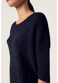 Marineblaues Strickpullover mit lockerer Passform, runder Ausschnitt und ärmellangen Ärmeln; verfügt über einen strukturierten Stoff für zusätzliche Wärme.