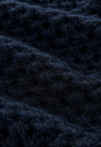 Navy modrý texturovaný materiál s huňatým, jemným vzhledem, který vystavuje vzor vyvýšených teček a bohatou, tmavou barvu.