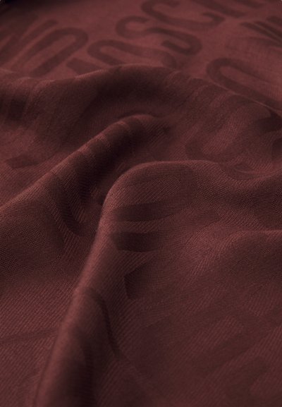 Tecido bordeaux com um subtil padrão elevado de letras, mostrando textura e suaves pregas na superfície.
