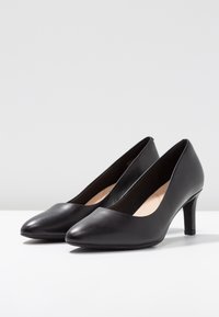 Escarpins en cuir noir avec un bout pointu, une texture lisse et une hauteur de talon modérée. Design simple et élégant sans ornements supplémentaires.