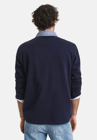 Jūrinis ilgomis rankovėmis marškiniai su apykakle, su šviesiai mėlyna apykakle ir rankogaliais. Pagaminti iš lygaus medvilnės mišinio, laisva forma.