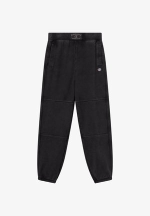 Czarne spodnie dresowe wykonane z miękkiego materiału, z elastycznym pasem, bocznymi kieszeniami oraz naszywką z logo na lewej udzie.