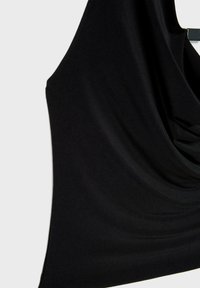 Crni bezrukavni top od glatke tkanine, s drapiranim dizajnom i blagom teksturom te suptilnim naborima, obješeni na vješalici.