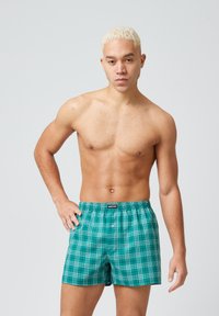 Groene geruite boxers met een elastische tailleband, met een geblokt patroon in meerdere tinten. De stof lijkt lichtgewicht te zijn.