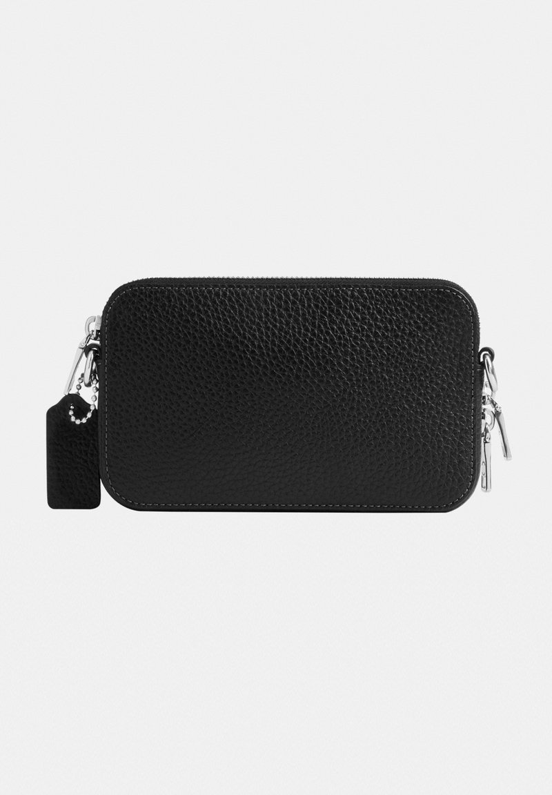 Bolsa negra con textura de cuero, con cremallera y herrajes plateados, y etiqueta rectangular adjunta sobre fondo blanco.